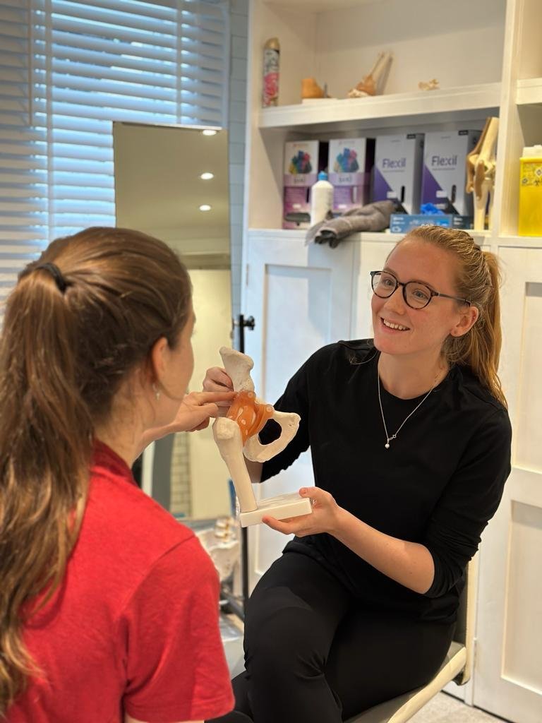 Women's health physiotherapist explaining to a patient the anatomy of the pelvis.