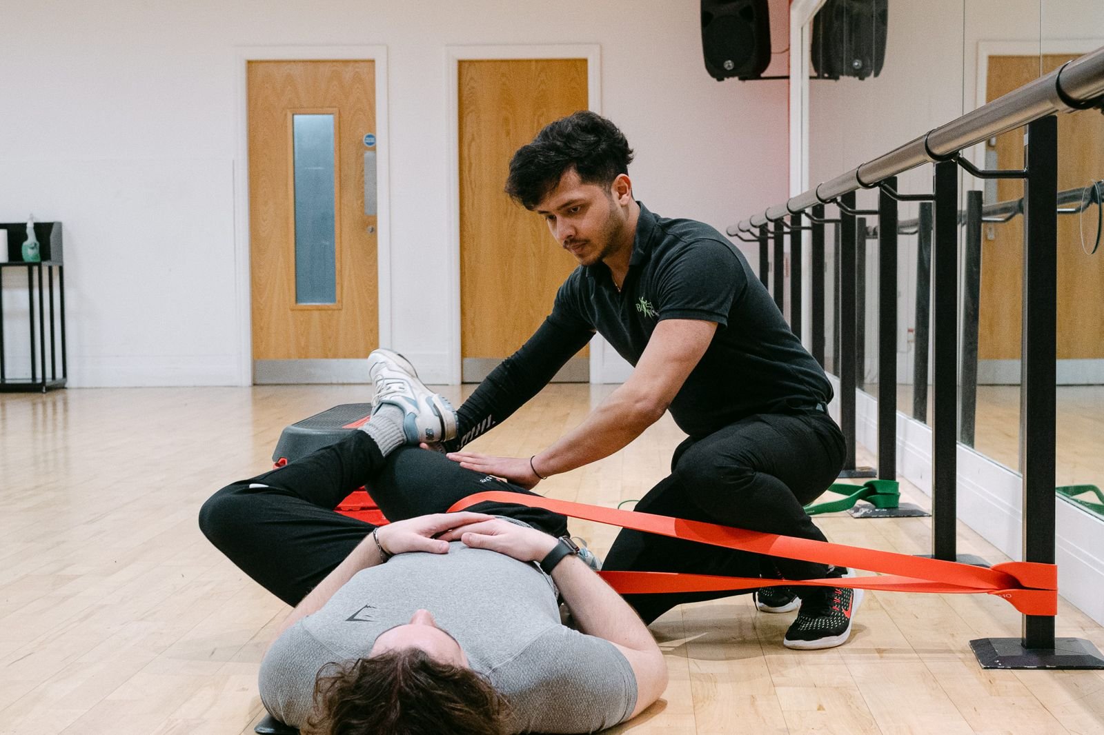 BOOST PHYSIO physiotherapist coaching a patient through a hip strengthening exercise with a band