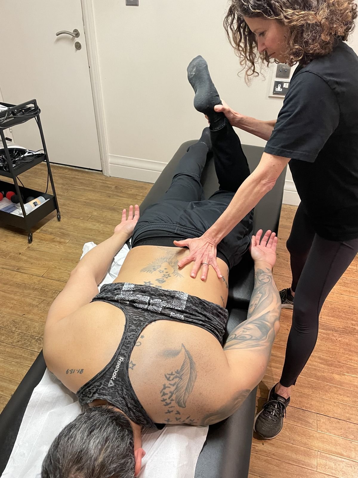 Physiotherapist assessing hip movement with a patient lying face down
