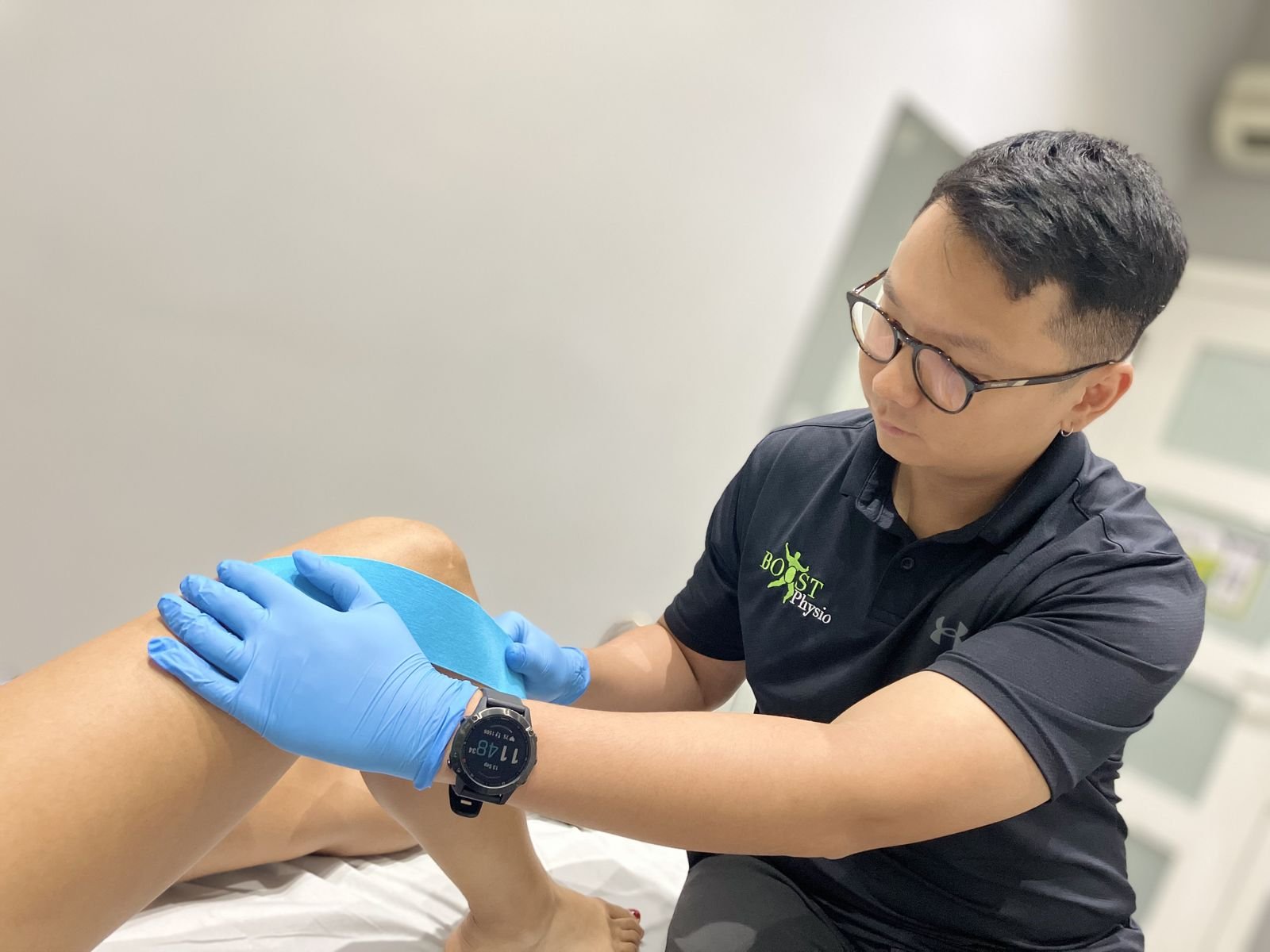 Physiotherapist applying supportive tape to a patient’s knee