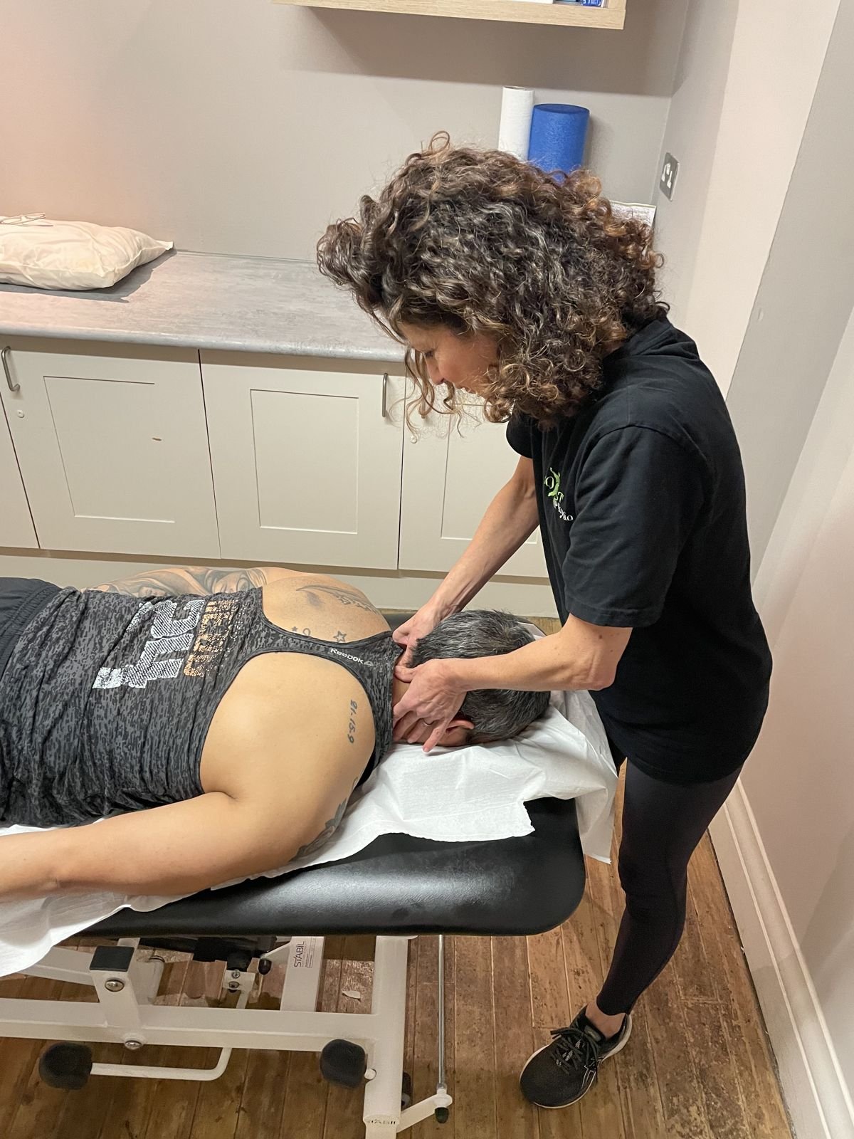 Physiotherapist mobilising the neck of a patient lying on a treatment couch