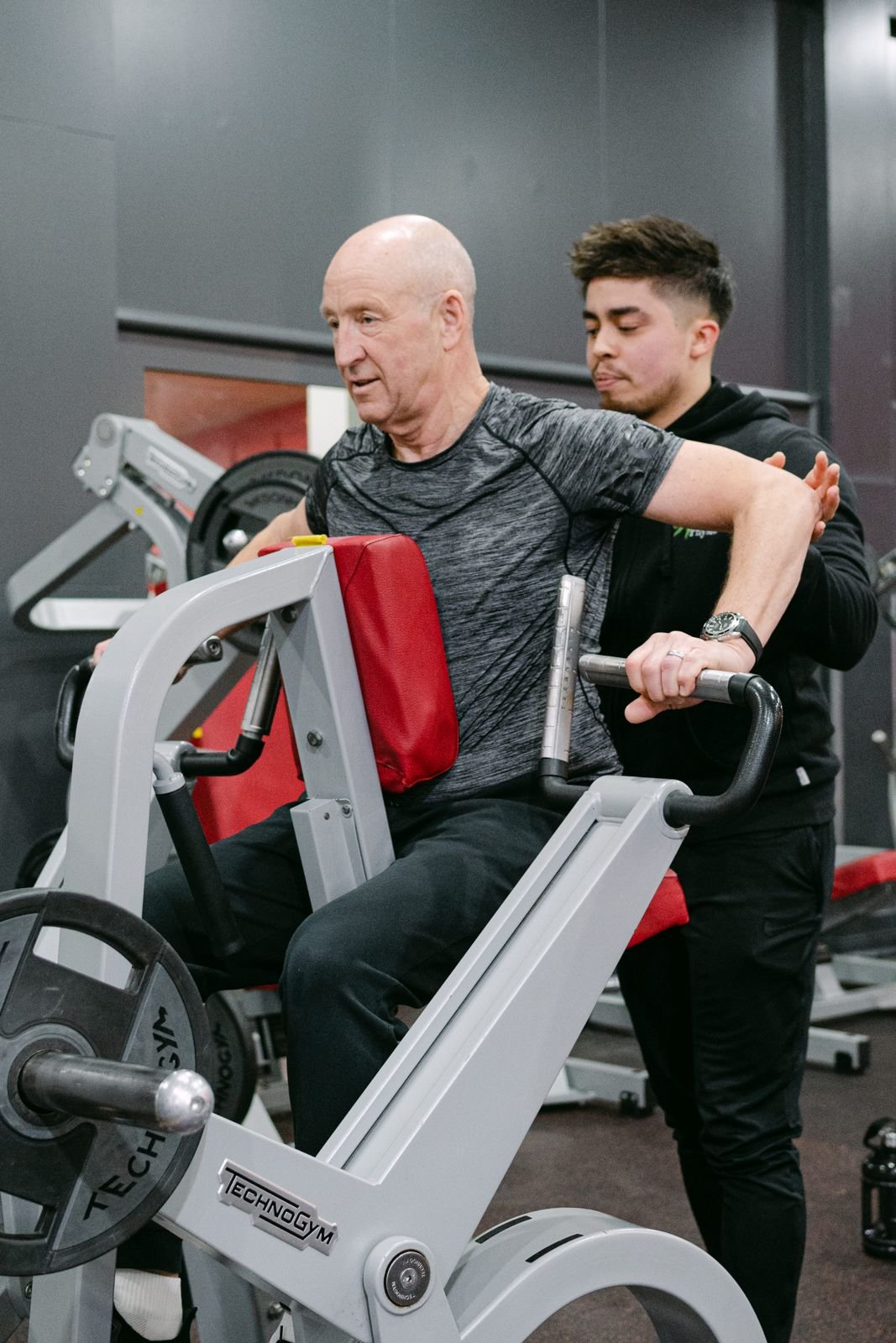 BOOST PHYSIO physiotherapist supporting an older man during gym-based strength training