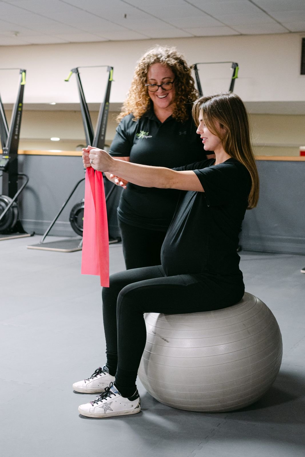 Pregnant woman doing a gentle exercise on a ball with a physiotherapist