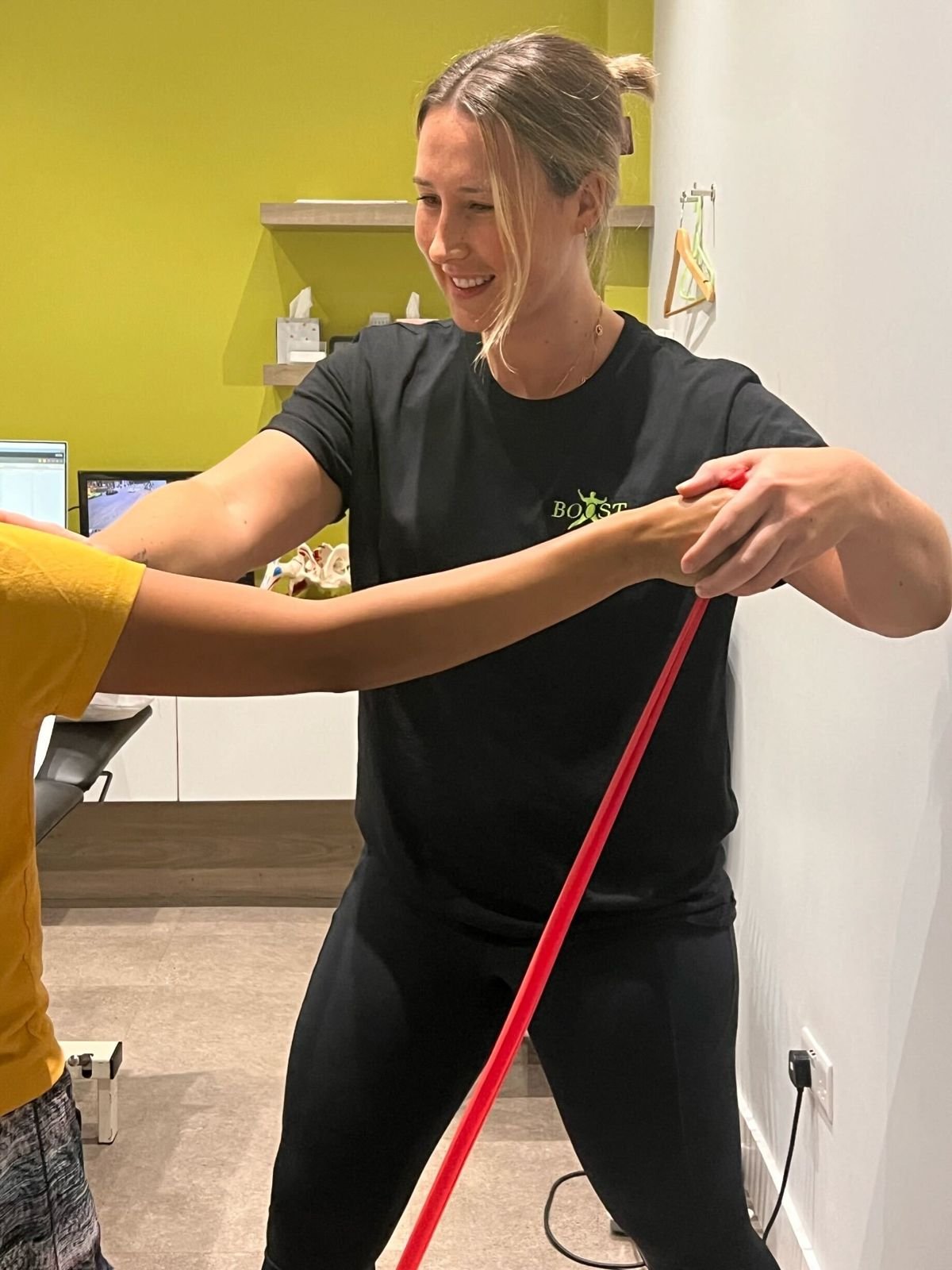 Physiotherapist guiding a patient through a resistance band shoulder exercise